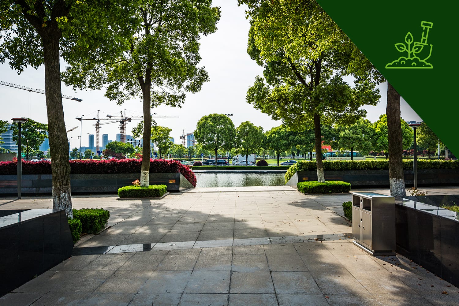 Espaço urbano com paisagismo corporativo, árvores alinhadas, canteiros floridos e visual sustentável.